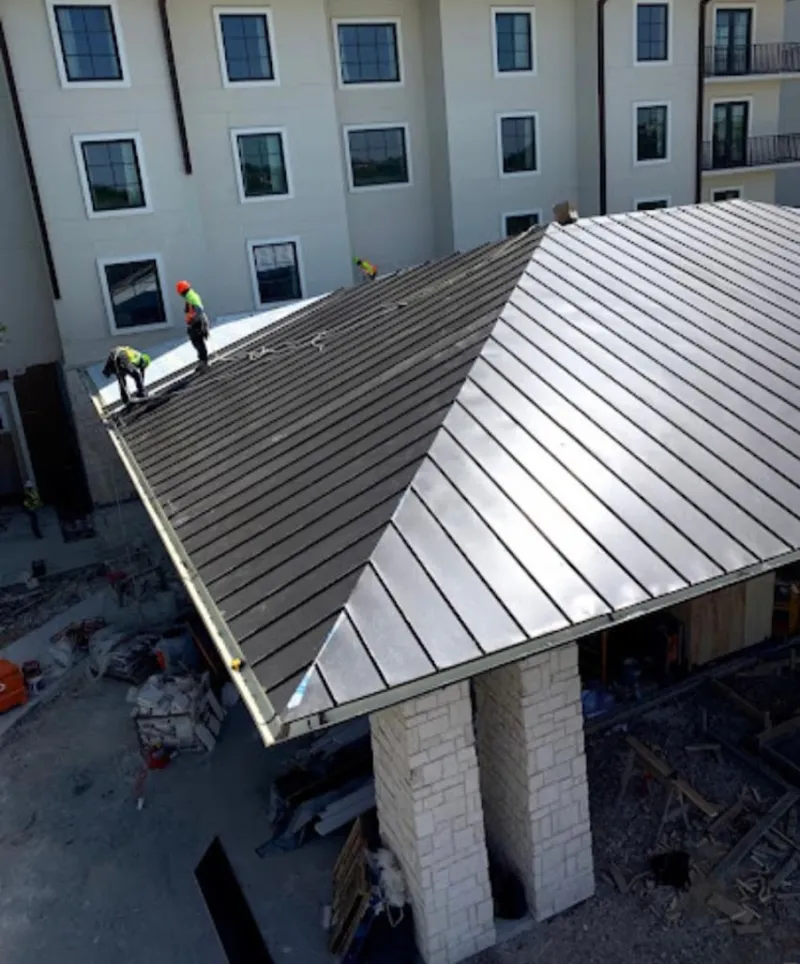 Crew installing standing seam metal roof panels on a commercial project in Yarmouth